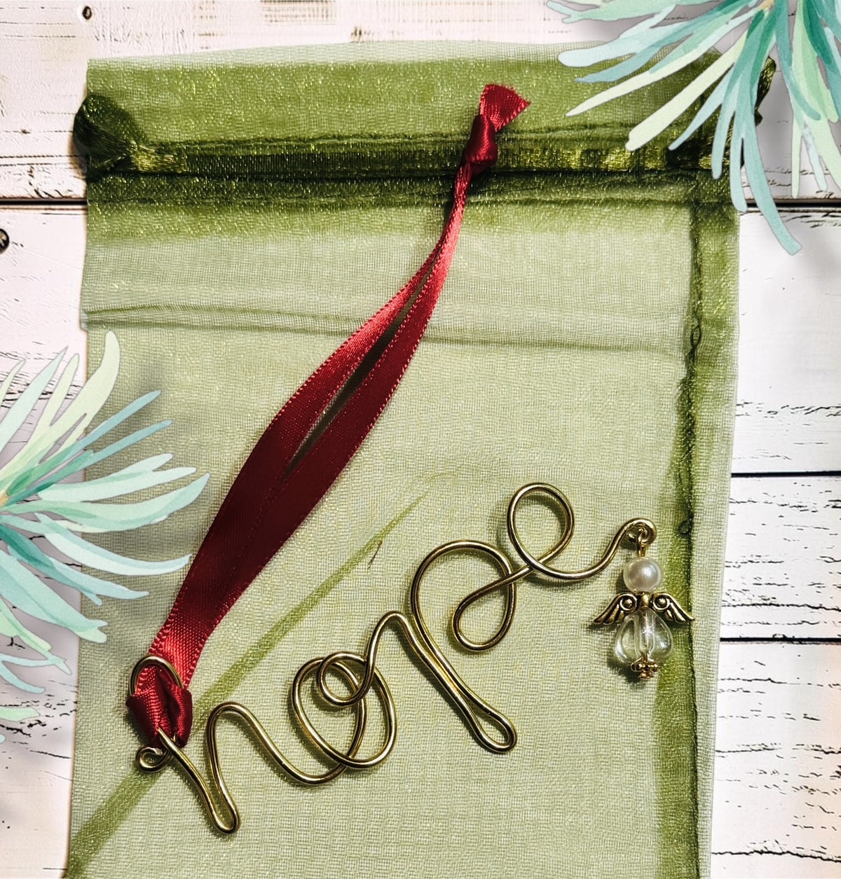 Handmade gold-tone wire word Christmas ornament with red ribbon on a Christmas tree