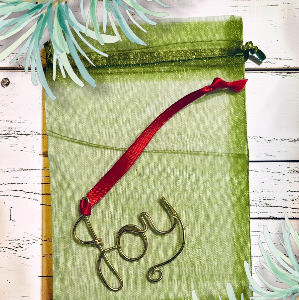 Close-up of a handmade gold-tone wire word Christmas ornament with red ribbon